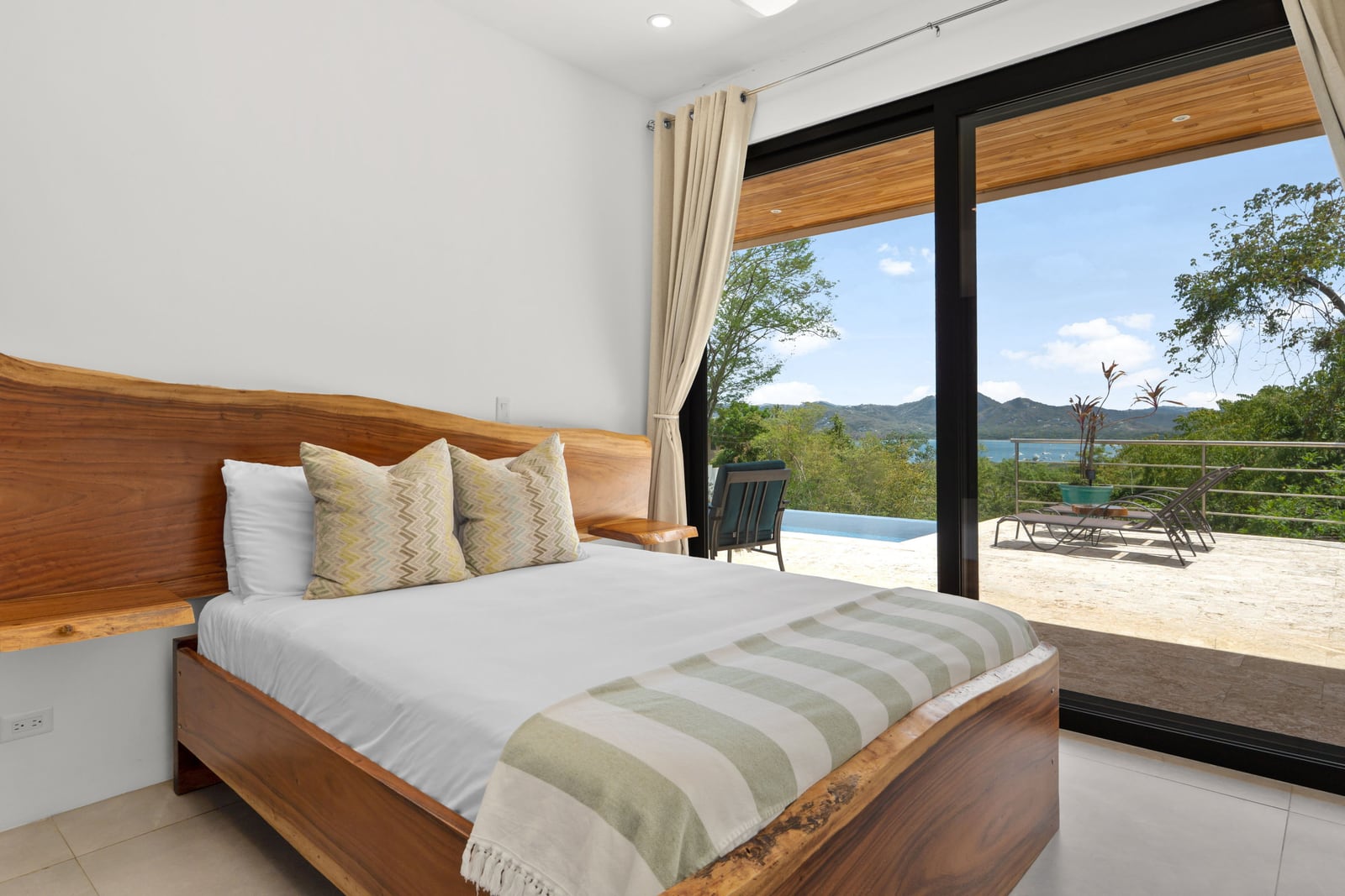 Bedroom at Casa Nina Flamingo with a live-edge headboard and doors straight out to the pool terrace