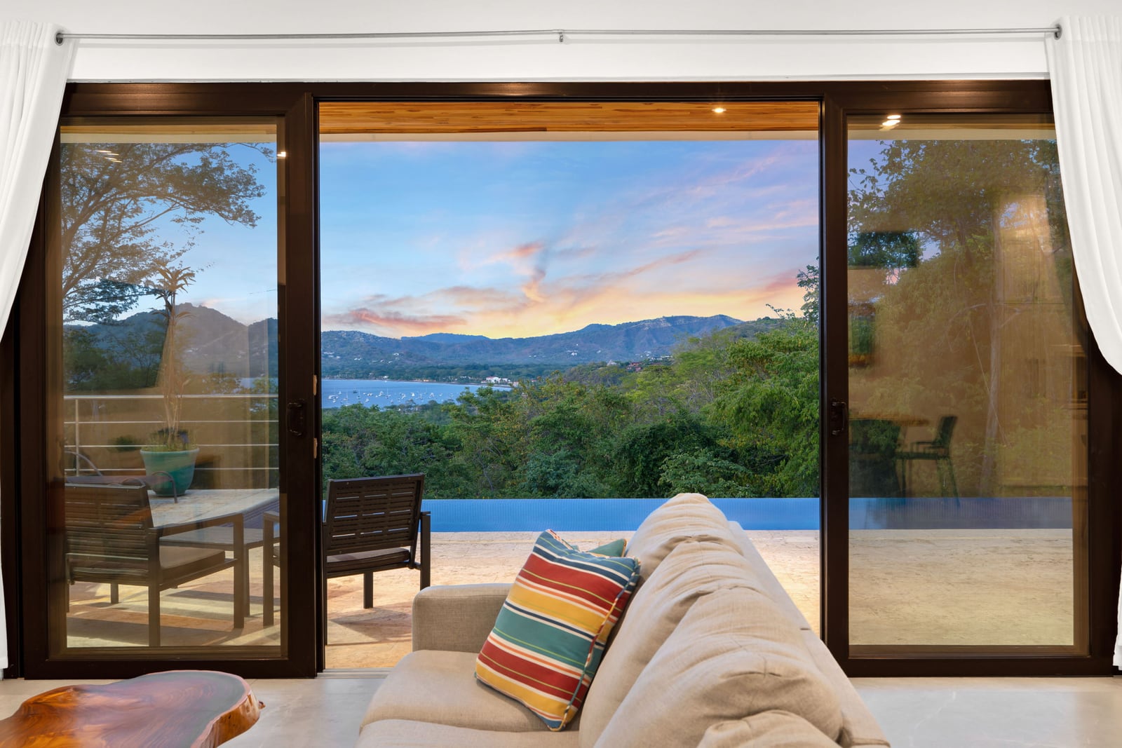 The living room doors slid open to the terrace, the bay and the hills at sunset, Casa Nina Flamingo